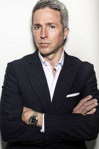 Portrait of mature businessman standing arms crossed against wall