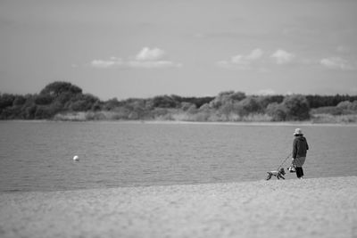 Man walking on beach against sky