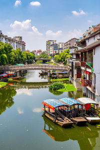 Canal by buildings against sky in city