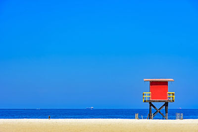 Lifeguard hut on beach against clear blue sky