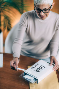Midsection of man holding smart phone on table