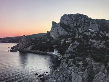 Rock formations in sea against sky during sunset