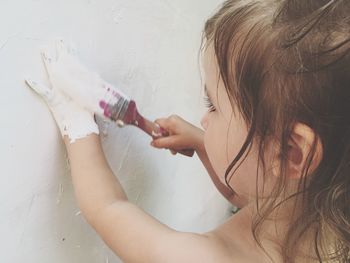 Close-up of girl painting wall at home