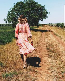 Rear view of woman walking on field