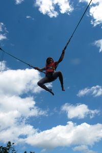 Low angle view of girl bungee jumping against sky