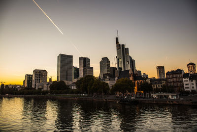 River and buildings against sky during sunset