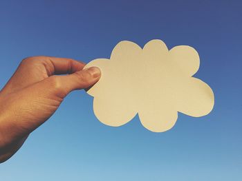 Close-up of hand holding text against clear blue sky