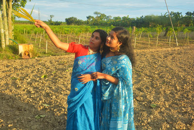 Friends holding crop standing at farm