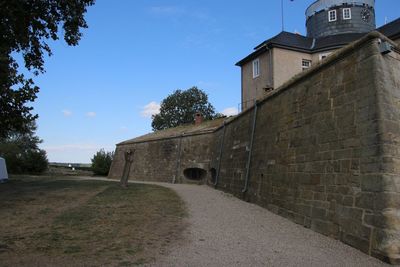 Footpath by old building against sky