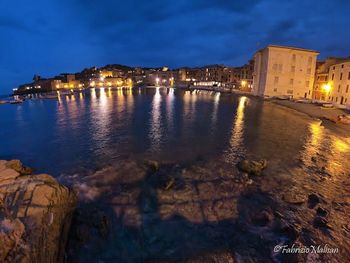 Illuminated buildings by sea at night