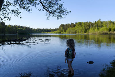 Rear view of woman by lake against sky