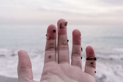 Close-up of hand holding bird against sea