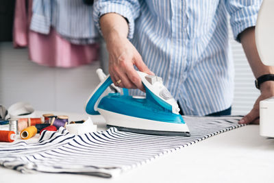 Midsection of craftswoman ironing textile at workshop