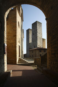 Low angle view of historic building against blue sky, san geminiano, tuscany, italy