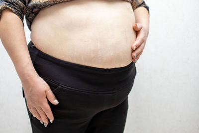 Midsection of woman holding while standing against wall