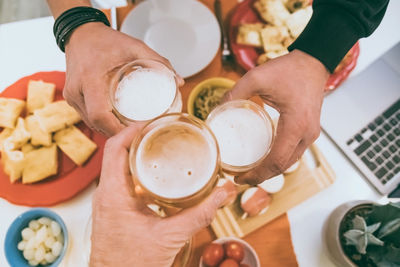 Toast with friend view from the top of a table with many foods and glasses of beer in hands cheer up