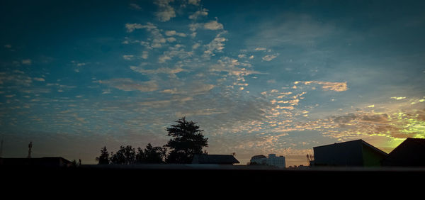 Silhouette trees and buildings against sky during sunset