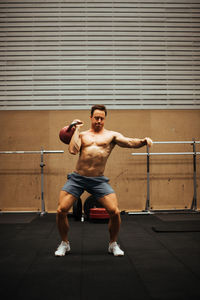 Full length of shirtless man sitting on wall