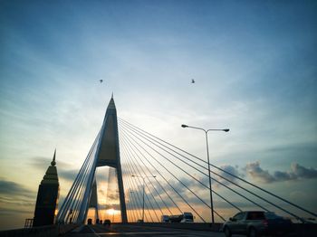 Low angle view of suspension bridge against cloudy sky