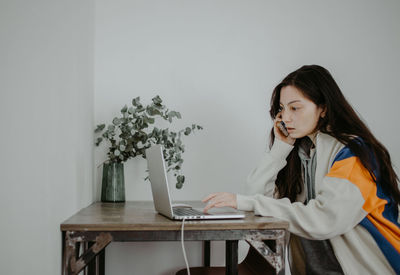 Young woman using laptop while sitting on table at home