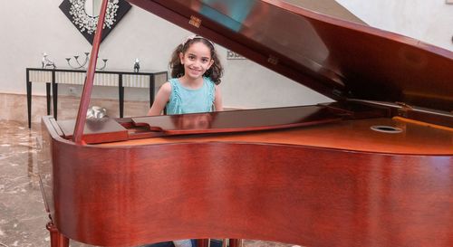 Portrait of smiling girl by piano