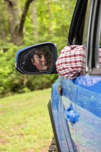 Reflection of man on side-view mirror