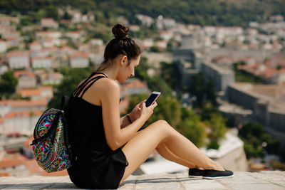 Woman using mobile phone on wall