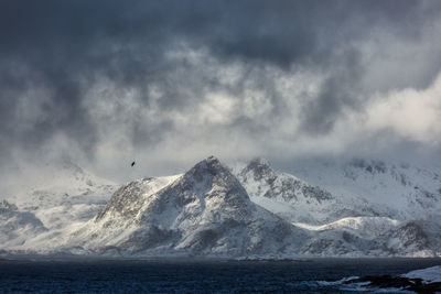 Scenic view of snowcapped mountains by sea during winter