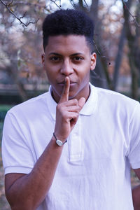 Portrait of young man with finger on lips over field