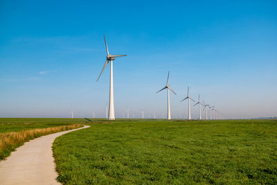 Windmills on field against sky