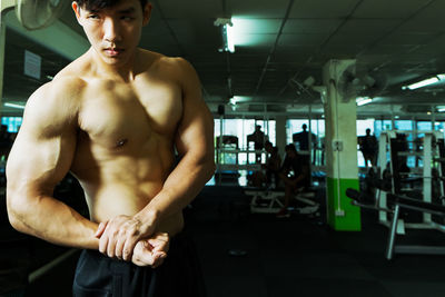 Shirtless muscular man flexing muscles at gym