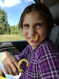 Portrait of happy girl eating snacks in car