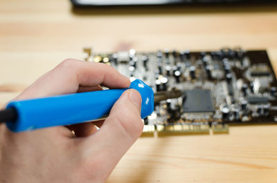 Cropped image of man soldering circuit board at table