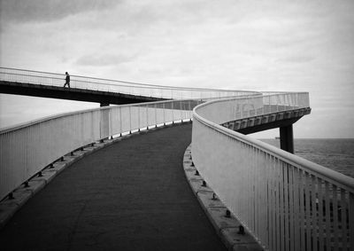 Rear view of person walking on narrow skywalk