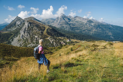 Rear view of man walking on mountain against sky