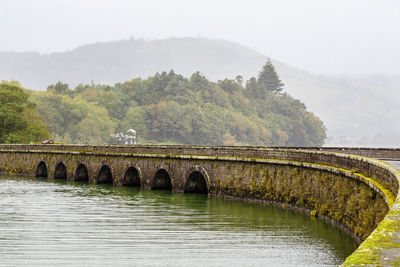 Arch bridge over river against mountains