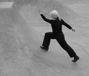 Woman in black exercises on the grey concrete pool in monochrome 