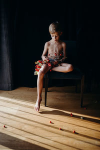 Full length of shirtless young woman lying on wood