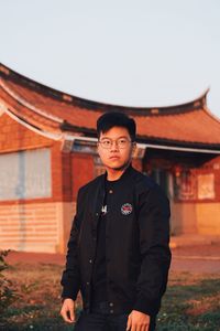 Portrait of young man standing against built structure