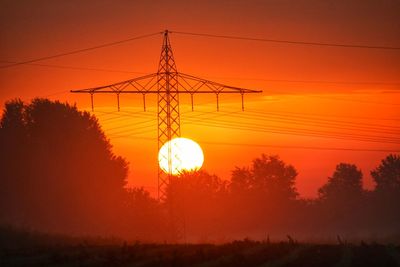 Low angle view of silhouette electricity pylon against romantic sky at sunset