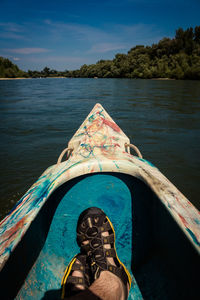 Low section of man on boat against river