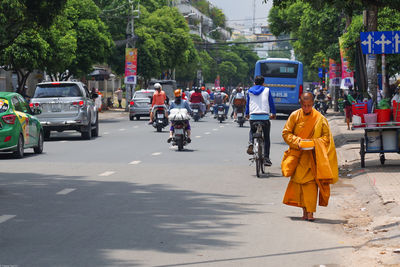 Rear view of people walking on road in city