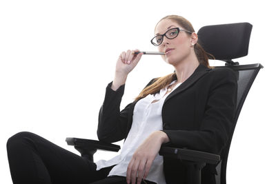 Portrait of businesswoman sitting on chair over white background