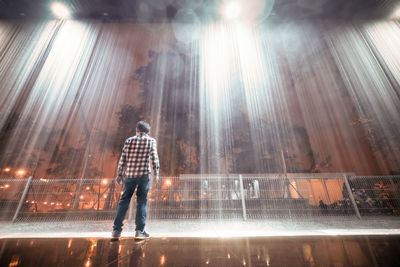 Rear view of man looking at illuminated building