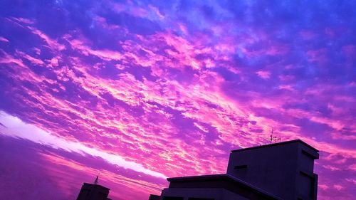 Low angle view of silhouette building against dramatic sky