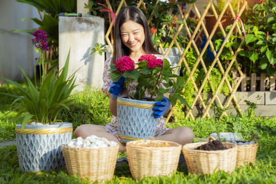 Woman holding flower pots in basket by plants