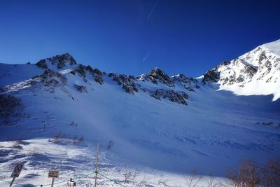 Scenic view of snow covered mountains against clear blue sky