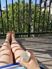 Low section of woman relaxing on railing