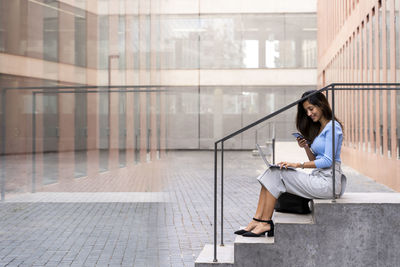 Young woman using mobile phone while sitting in office