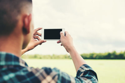 Midsection of man using mobile phone against sky